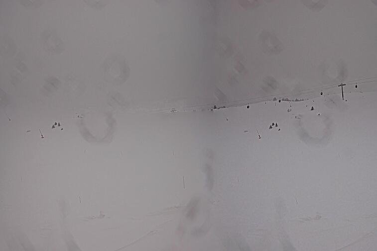 Birds-eye webcam view of conditions on the pistes above Courchevel 1650. The top station of the Ariondaz cable car is visible on the left-hand side of the shot.