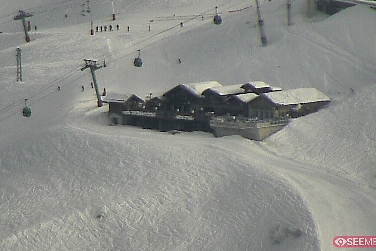 Webcam view of the Folie Douce mountain restaurant in Meribel.  In the background are the Biche (blue) and Maudit (red) pistes; and the pictured lift/mid-station is the Saulire Express.